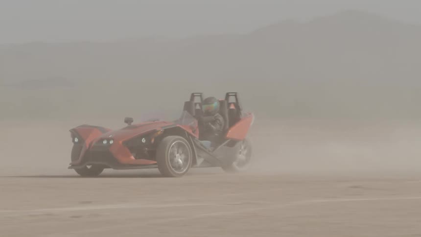 A polaris slingshot being driven through the desert