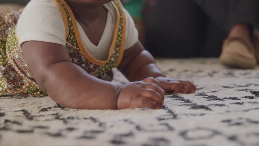 A baby lies on the carpet