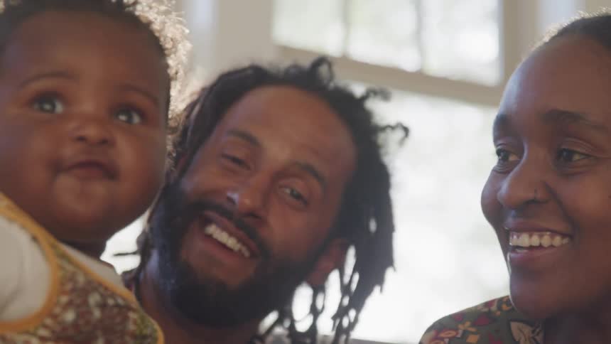 A man and woman smile and laugh with their baby