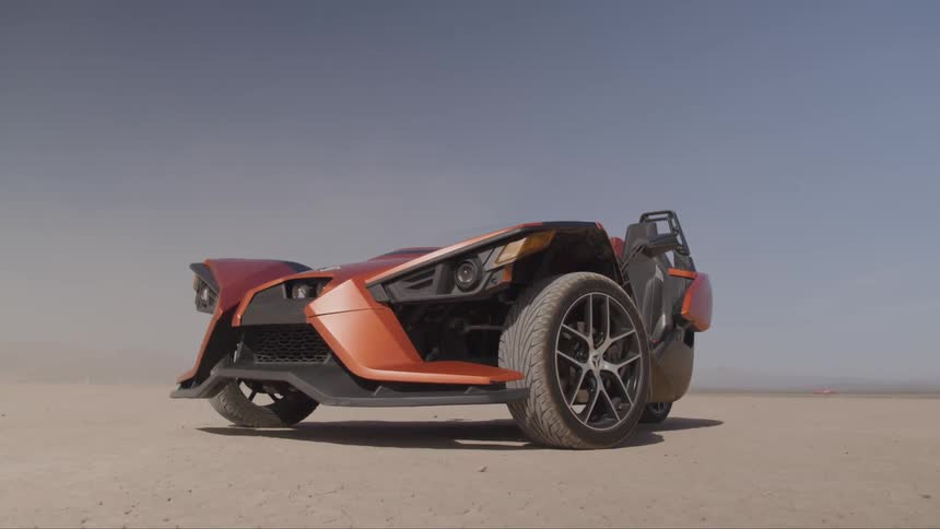 A three wheel sports vehicle is parked in the desert