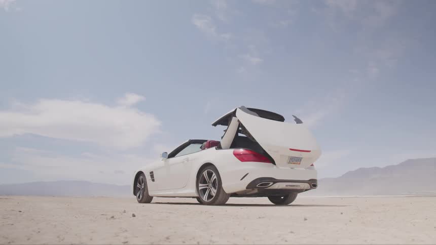 A convertible car in the desert putting up its top
