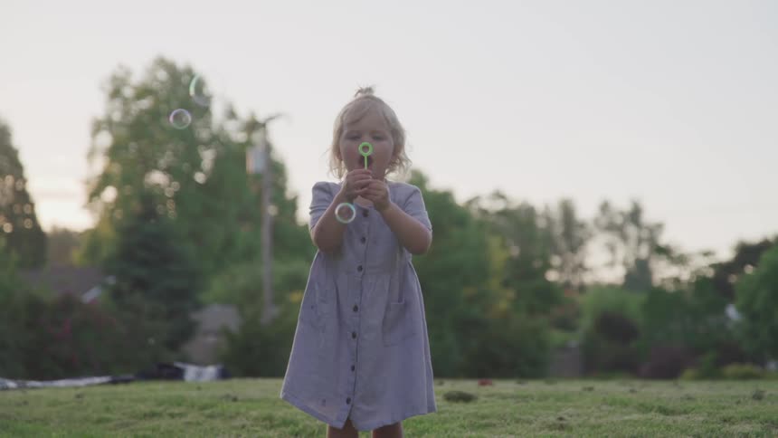 A young girls blows bubbles in the air