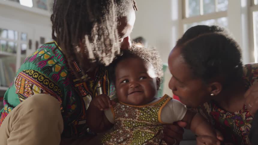 A man and woman kiss and play with a baby