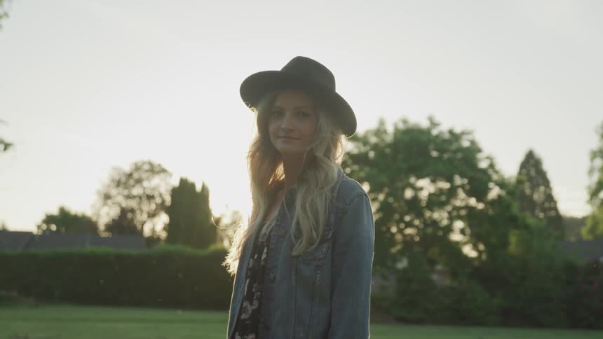 A woman stands outside in the sunshine and looks around