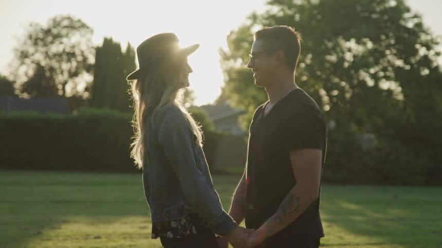 A young woman stand and hold hands while looking at one another