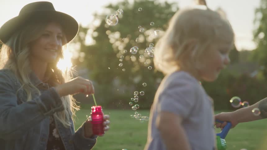 Family makes bubbles outdoors in field