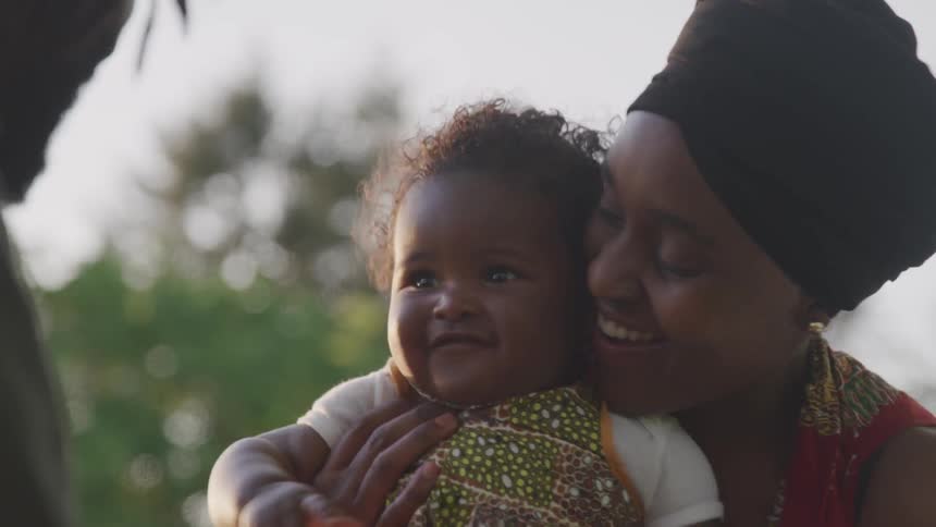 A woman smiles and plays with a baby