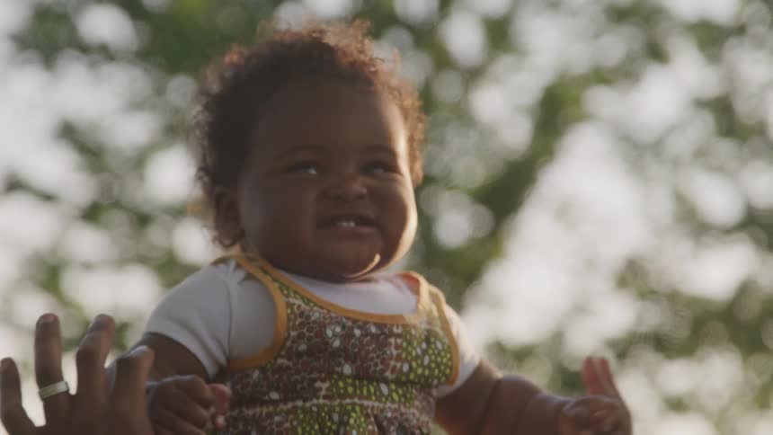 A baby sitting on a person playing outside