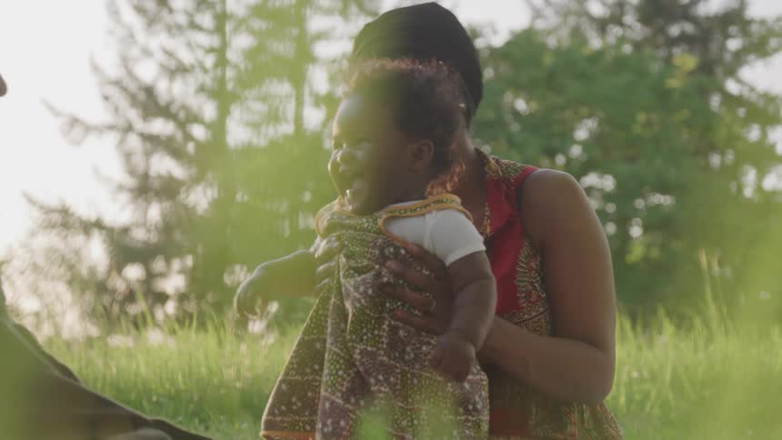 A mother and father play with their daughter outside on the grass
