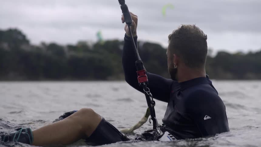 A man with a board attached to his feet sits in the water