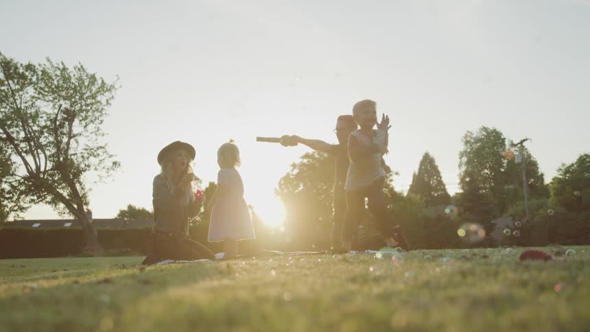 A white family blows bubbles and plays outdoors