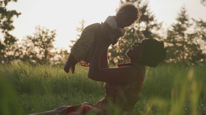 A young woman holds a baby in her lap and smiles and laughs