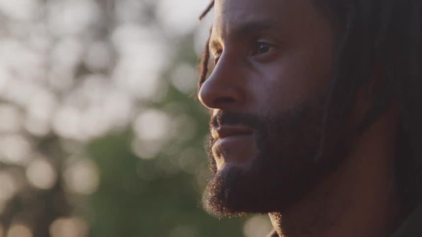 A man outside staring into the distance with sunlight on his face