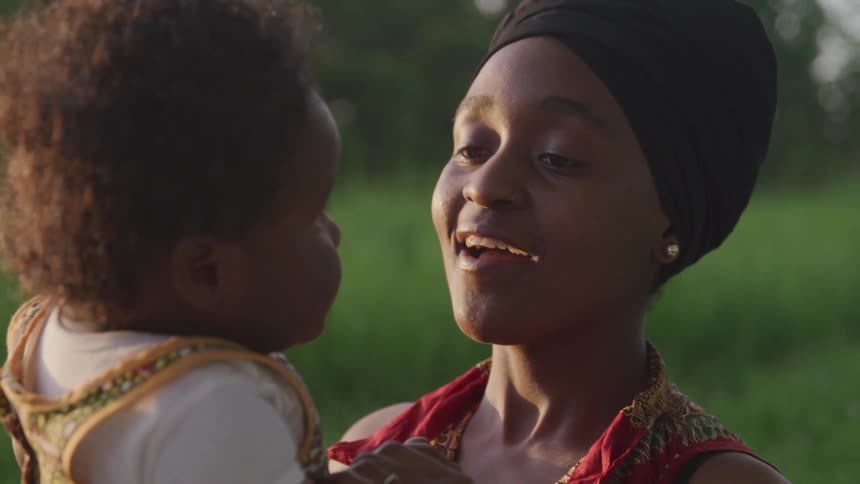 A woman smiles at a baby in her arms