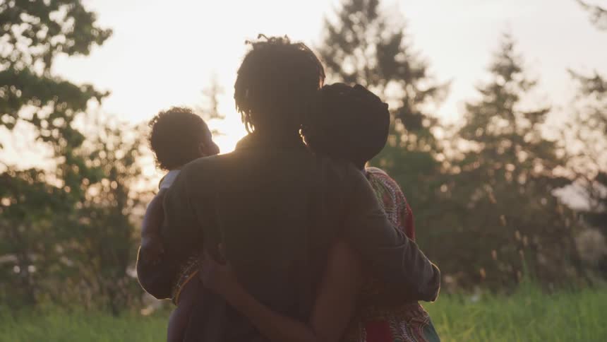 Woman and husband are holding their child outdoors