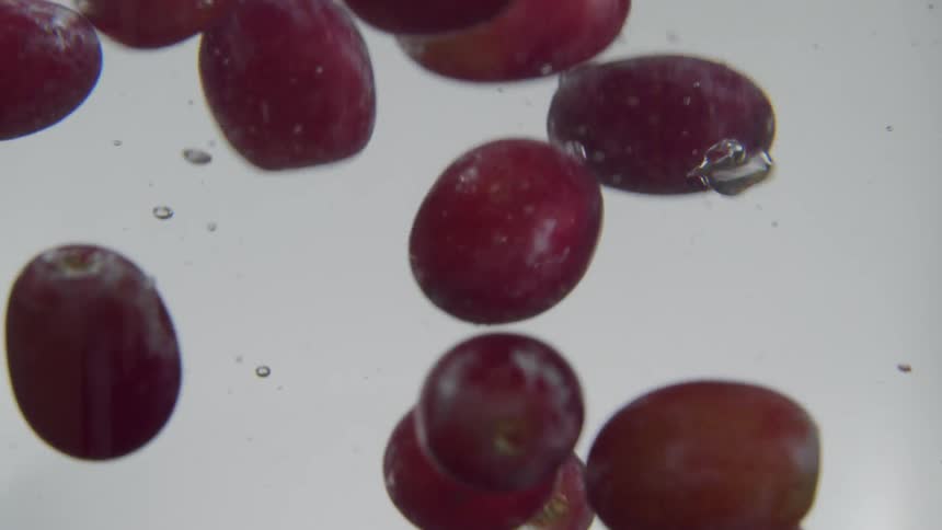 Many grapes being dropped into water