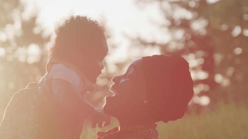 A woman is holding her baby outdoors