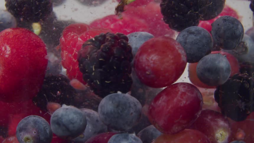 Berries in a bowl of water being stirred