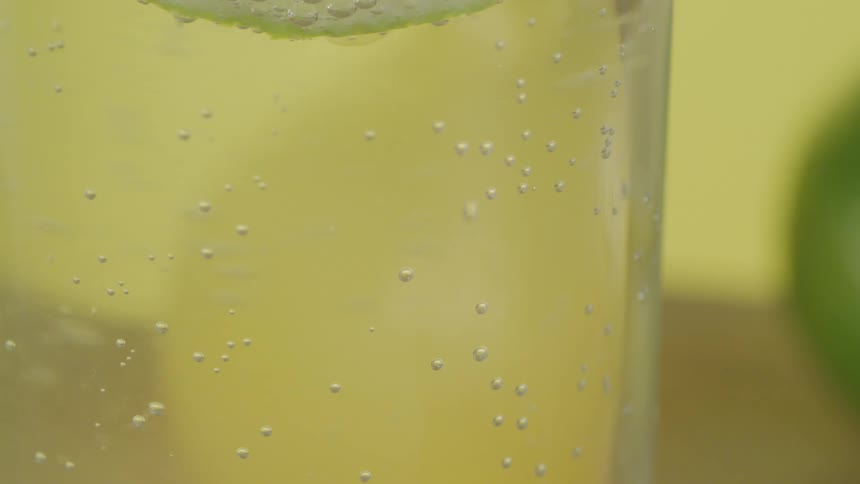 A translucent liquid in a glass against a yellow wall