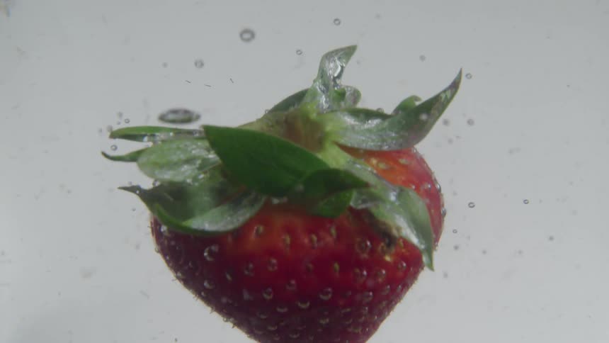 A strawberry falls into water