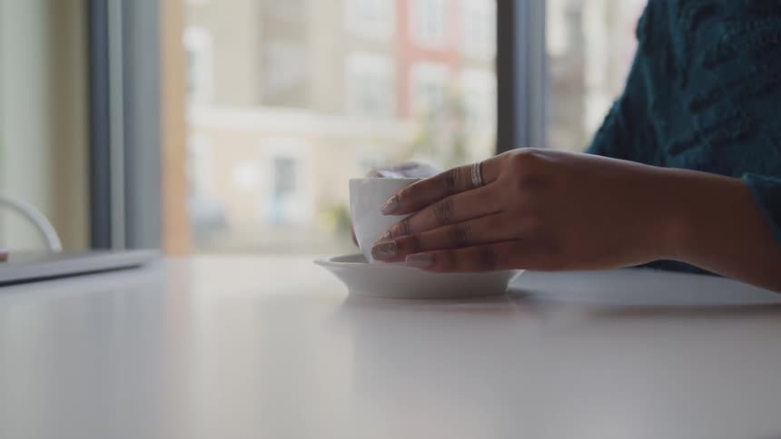 A young woman sets her mug down after taking a sip