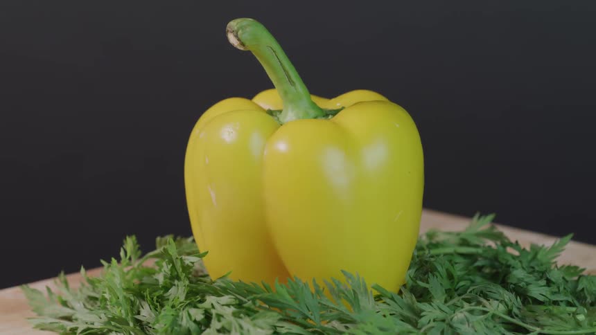 A yellow pepper on a bed of herbs
