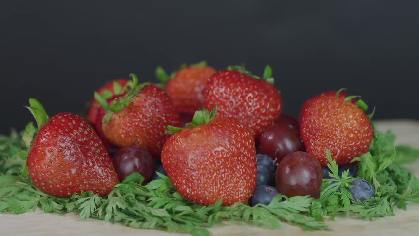 Strawberries and grapes and blueberries sitting on bed of leaves