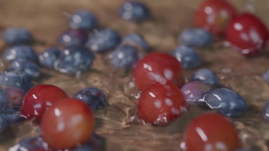 Grapes and blueberries are dropped onto a washing board