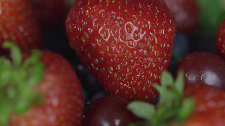Light glints on a pile of strawberries and grapes