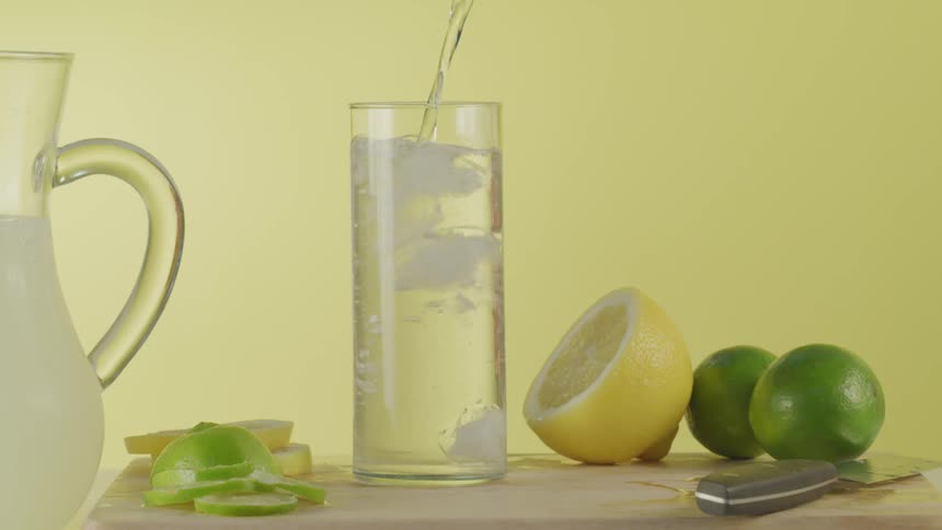 Water being poured into a tall glass on a cutting board