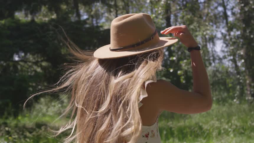 A girl in a hat moving through a woodland