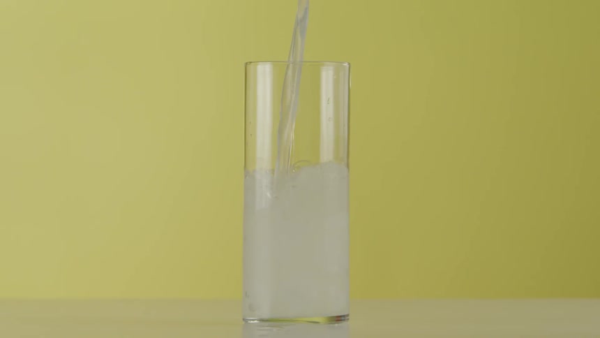 Liquid being poured over ice in a clear glass