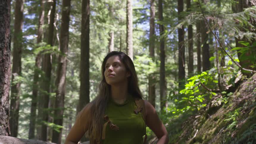 A woman is hiking through a forest area