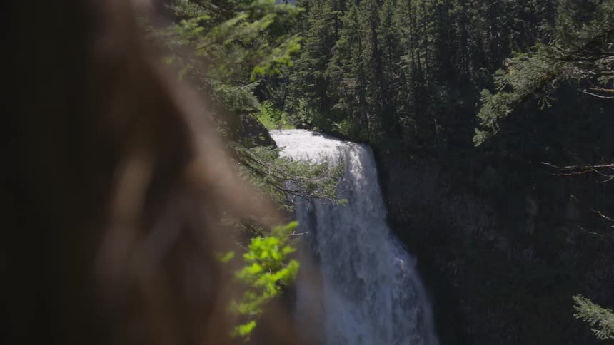 Woman stare into a waterfall in the middle of a forest