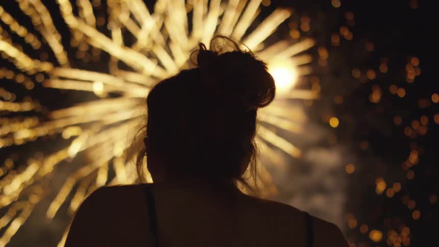 A woman watches fireworks at night