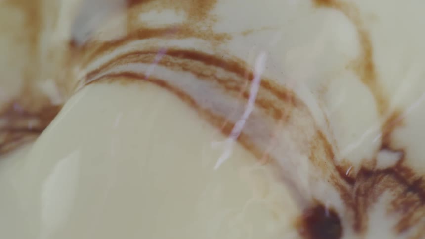 A shiny surface with a creamy color has ribbons and splotches of brown interspersed