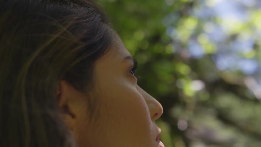 Woman looks up through trees contemplatively