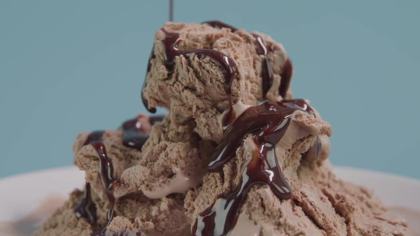 Chocolate syrup being poured on chocolate ice cream
