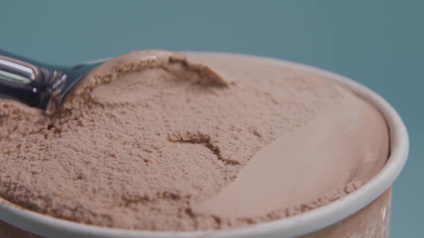 An ice cream scoop pulls out chocolate ice cream