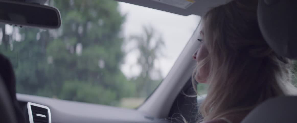 Woman sits in the passenger seat of a moving vehicle