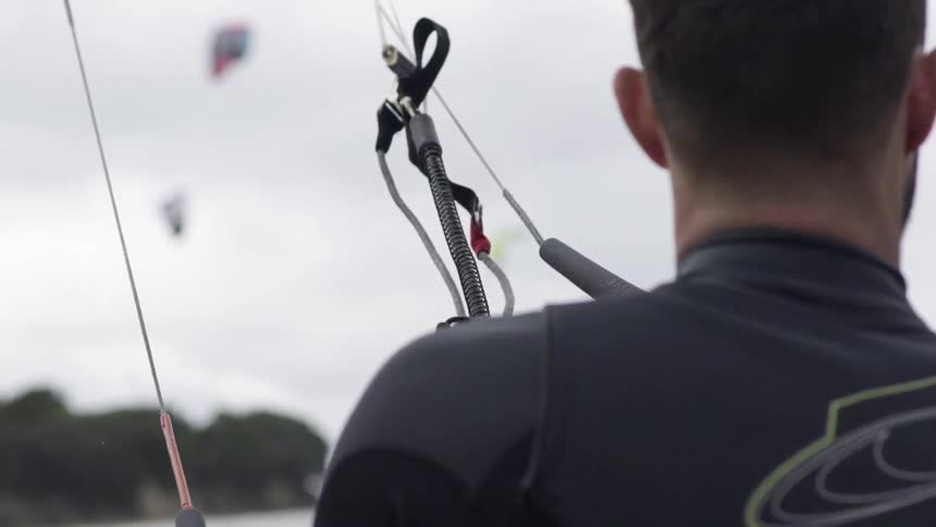 Person wearing a wetsuit standing by the water preparing for a session.