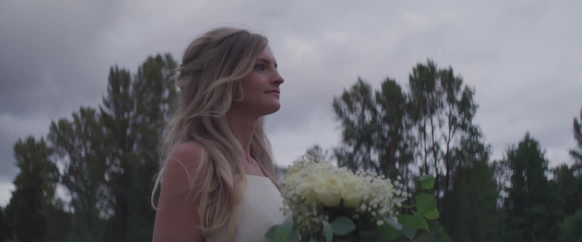 A woman in a wedding dress is walking with a bouquet