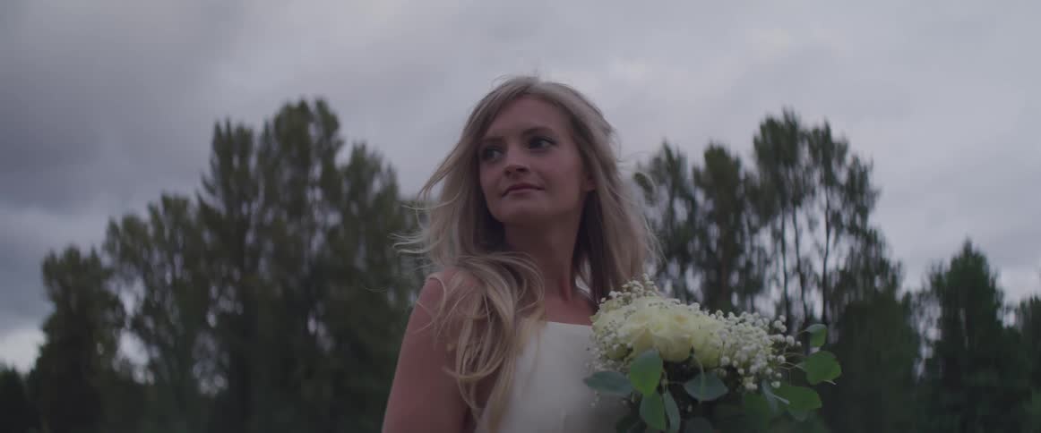 A bride poses outdoors holding her bouquet