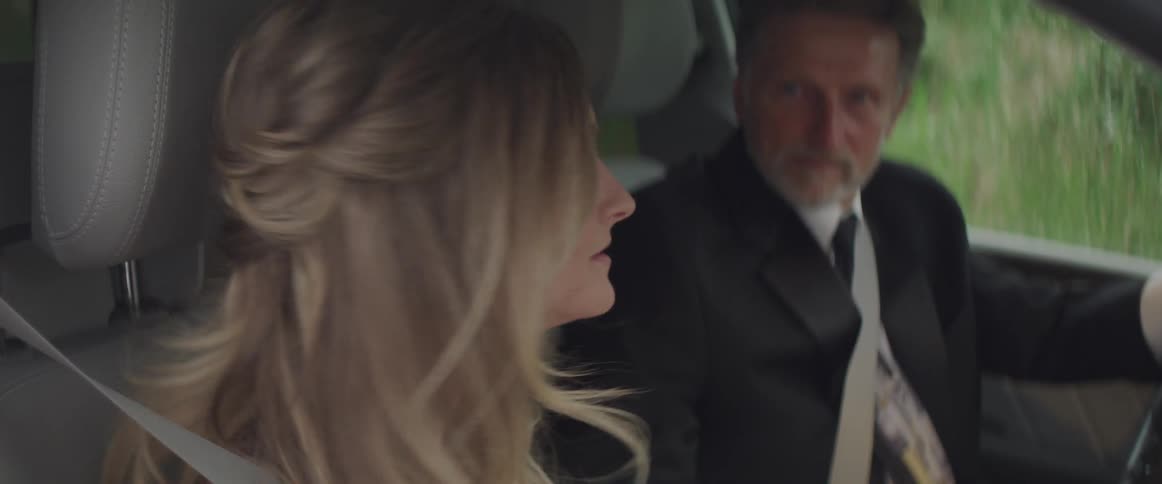 A man smiles at a woman as they sit in a vehicle