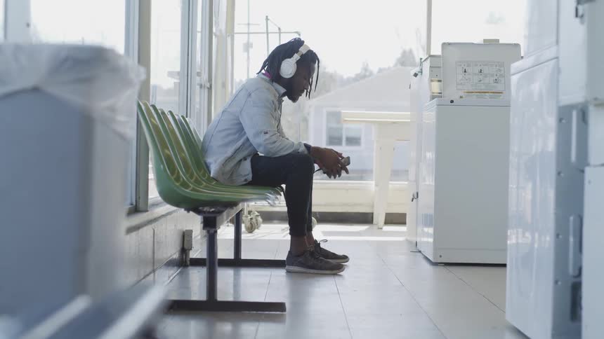 Black man sitting on bench listening to head phones