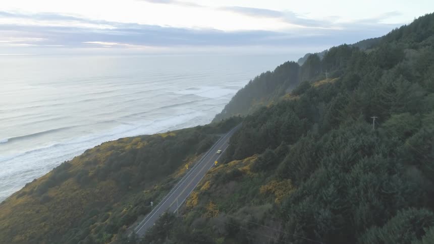 A high up view of a cliff surrounded by the ocean at sunrise