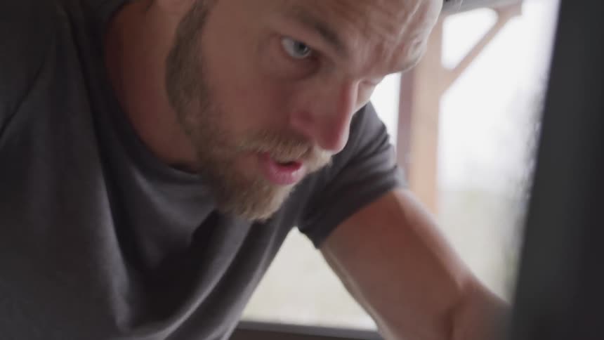 Blonde bearded man works out in gym during daylight