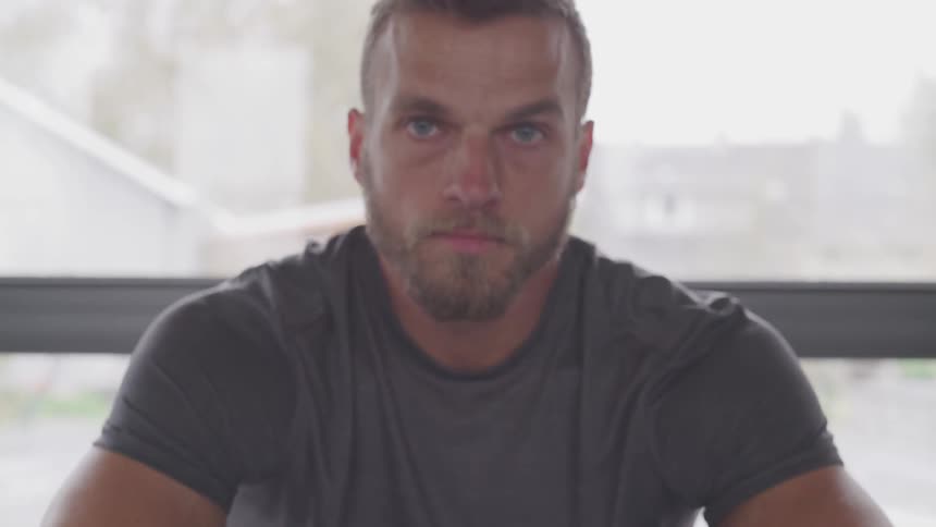Male sitting in front of a large window looking directly at the camera