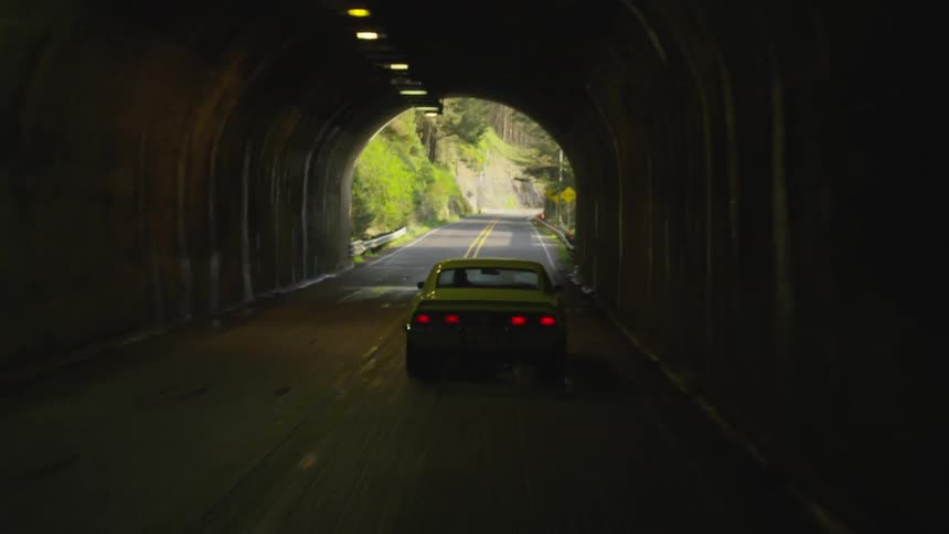 A yellow car driving through a tunnel