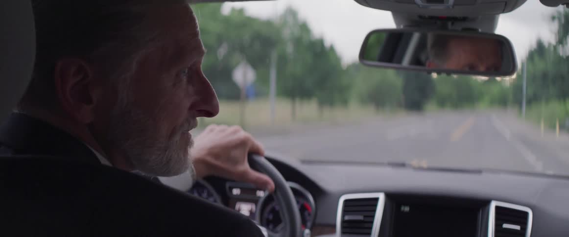 Man turns his head to the right while driving a car and then turns back to look forward at the road again